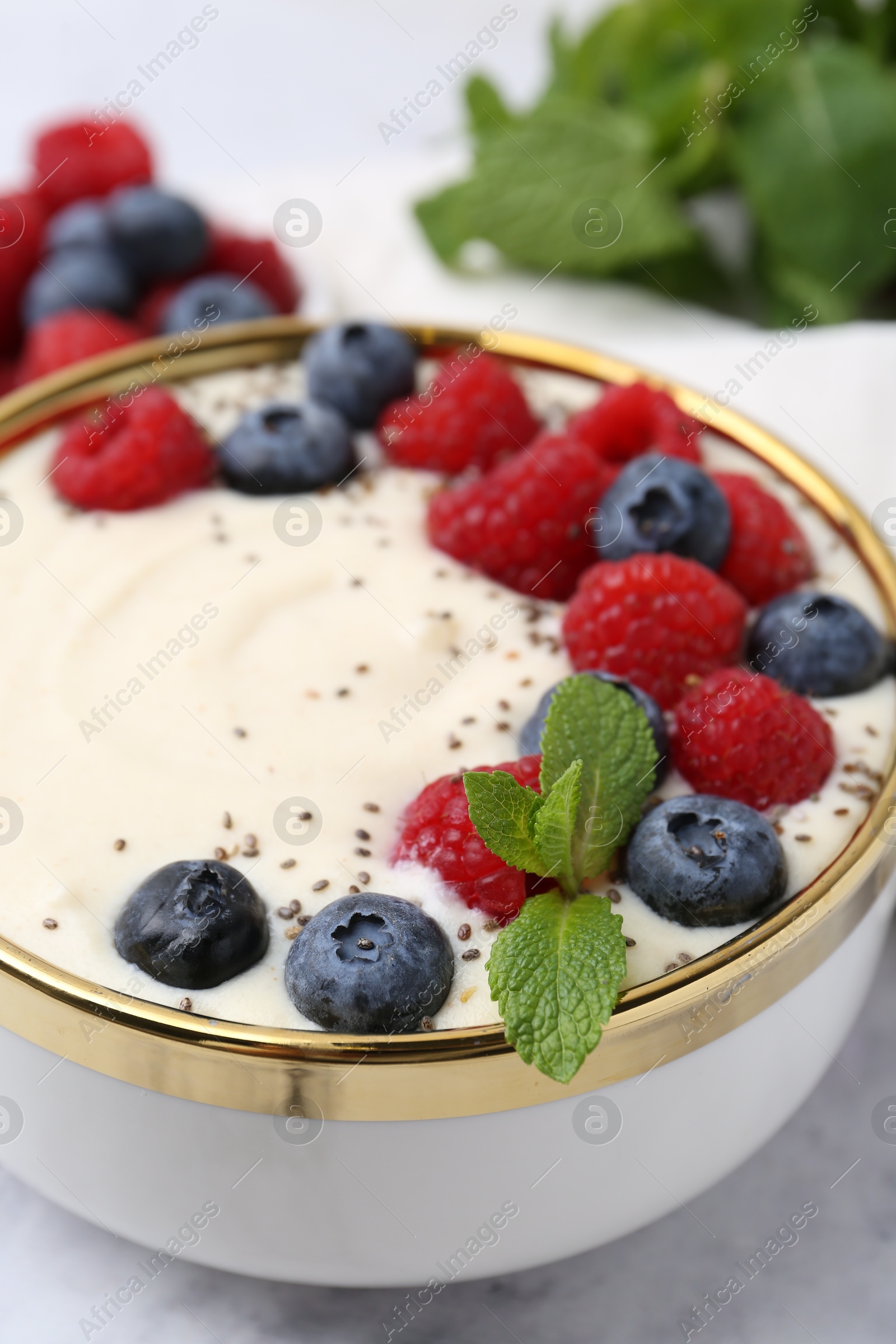 Photo of Tasty cooked semolina porridge with berries and mint on table, closeup