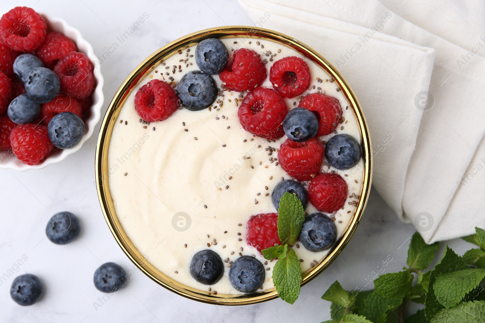 Photo of Tasty cooked semolina porridge with berries and mint on white marble table, top view