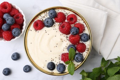 Photo of Tasty cooked semolina porridge with berries and mint on white marble table, top view