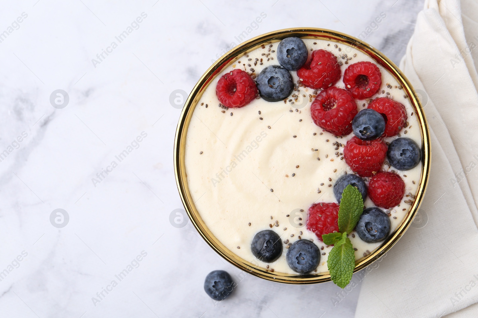 Photo of Tasty cooked semolina porridge with berries and mint on white marble table, top view. Space for text