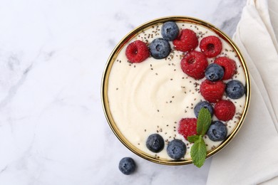 Photo of Tasty cooked semolina porridge with berries and mint on white marble table, top view. Space for text