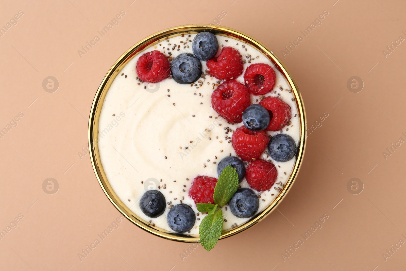 Photo of Tasty cooked semolina porridge with berries and mint on pale brown background, top view