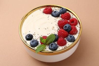 Tasty cooked semolina porridge with berries and mint on pale brown background, closeup