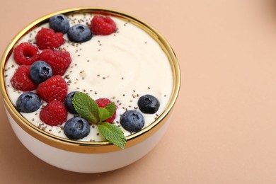 Photo of Tasty cooked semolina porridge with berries and mint on pale brown background, closeup. Space for text