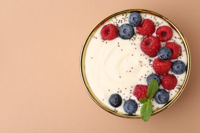 Photo of Tasty cooked semolina porridge with berries and mint on pale brown background, top view. Space for text