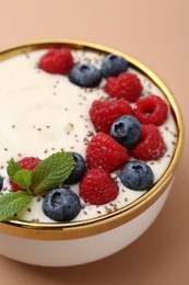 Photo of Tasty cooked semolina porridge with berries and mint on pale brown background, closeup