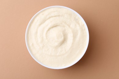 Photo of Tasty cooked semolina porridge in bowl on pale brown background, top view