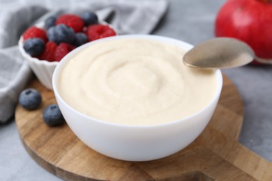 Photo of Tasty cooked semolina porridge in bowl and berries on grey table, closeup