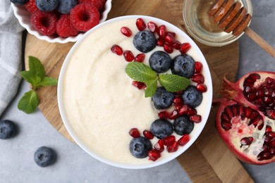 Photo of Tasty cooked semolina porridge with berries served on grey table, top view