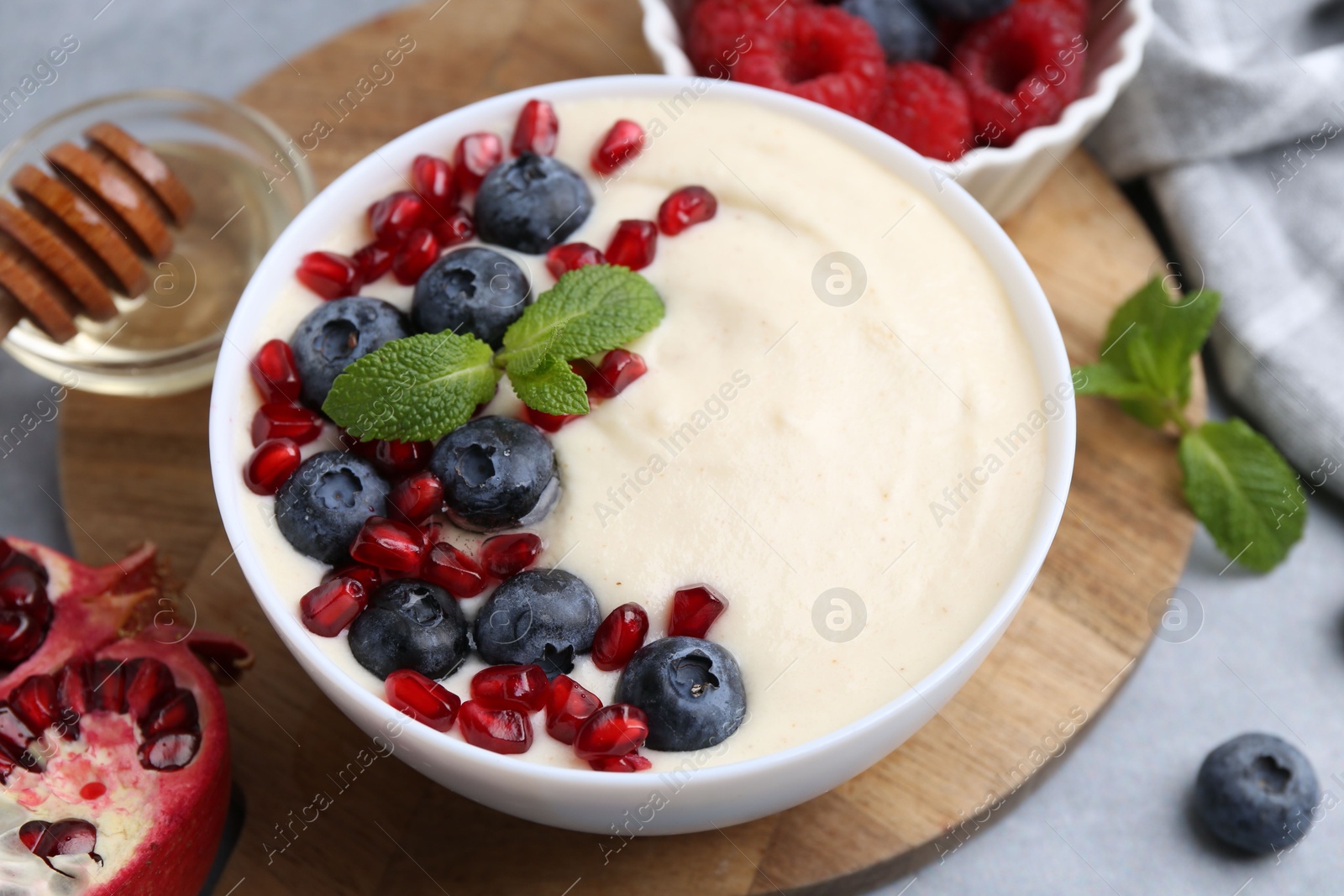 Photo of Tasty cooked semolina porridge with berries served on grey table, closeup