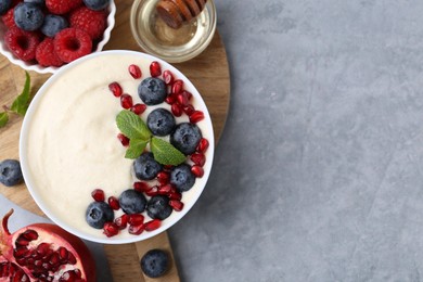 Photo of Tasty cooked semolina porridge with berries served on grey table, top view. Space for text