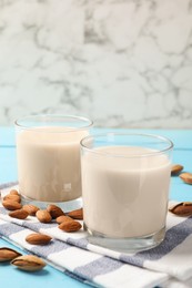 Glasses of almond milk and nuts on blue wooden table