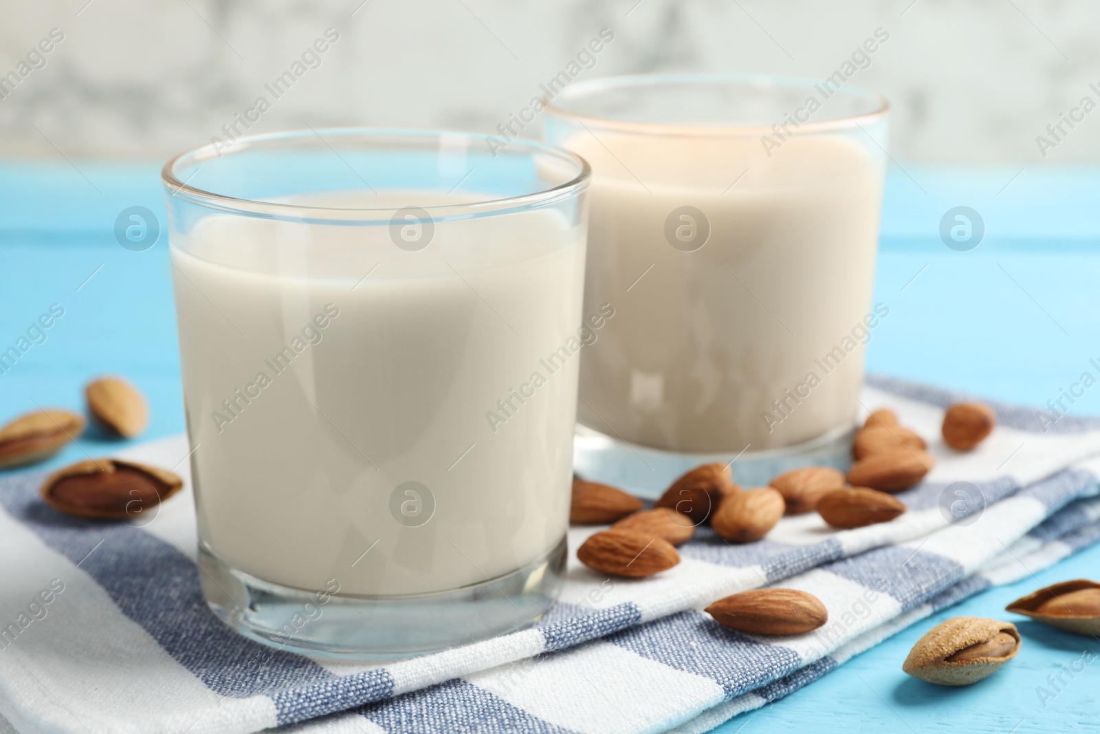 Photo of Glasses of almond milk and nuts on blue wooden table, closeup