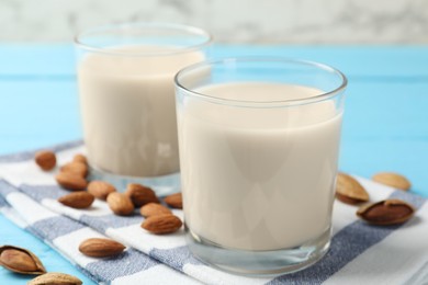 Glasses of almond milk and nuts on blue wooden table, closeup