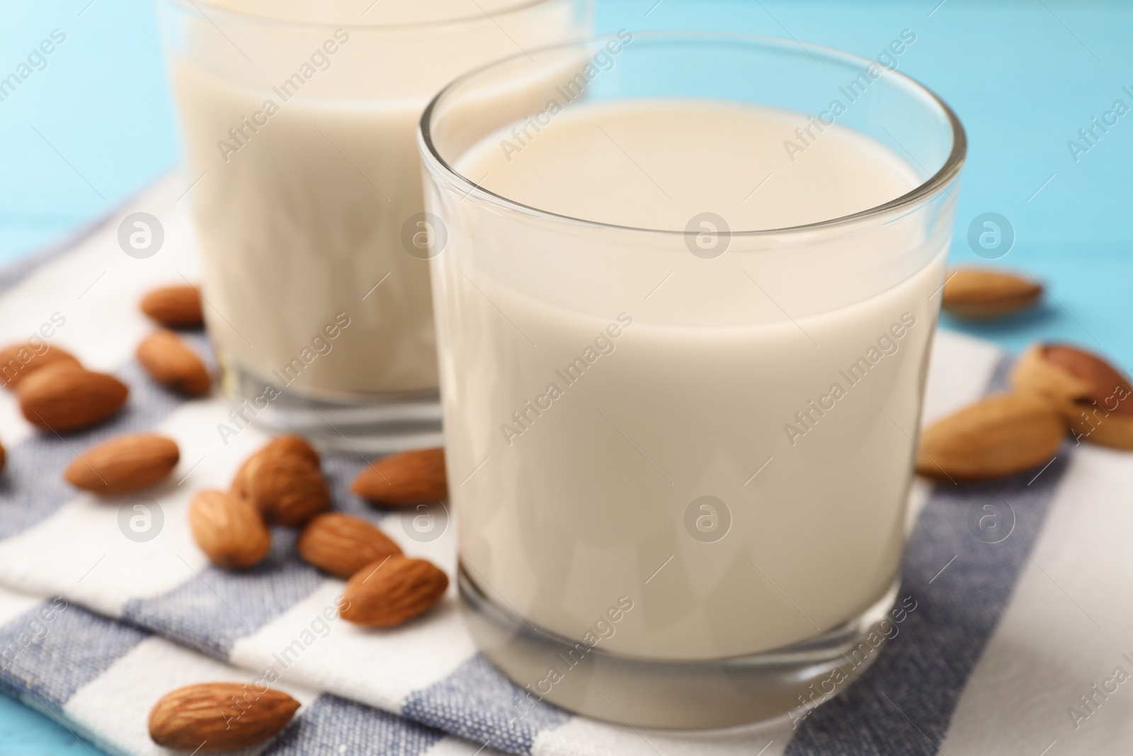 Photo of Glasses of almond milk and nuts on blue table, closeup