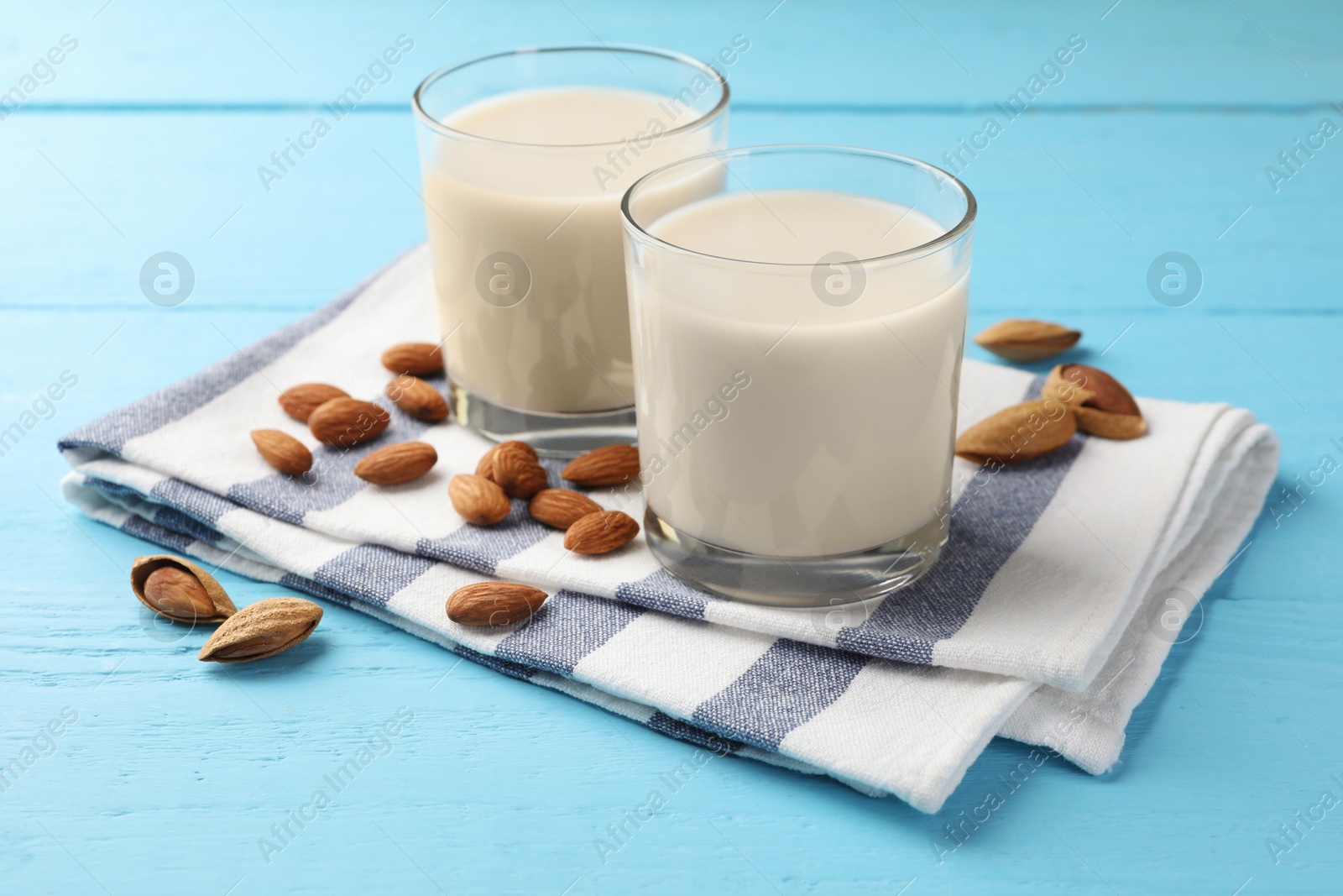 Photo of Glasses of almond milk and nuts on blue wooden table