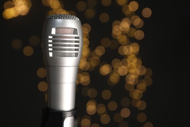 Photo of Sound recording and reinforcement. Microphone against black background with blurred lights, closeup. Space for text.