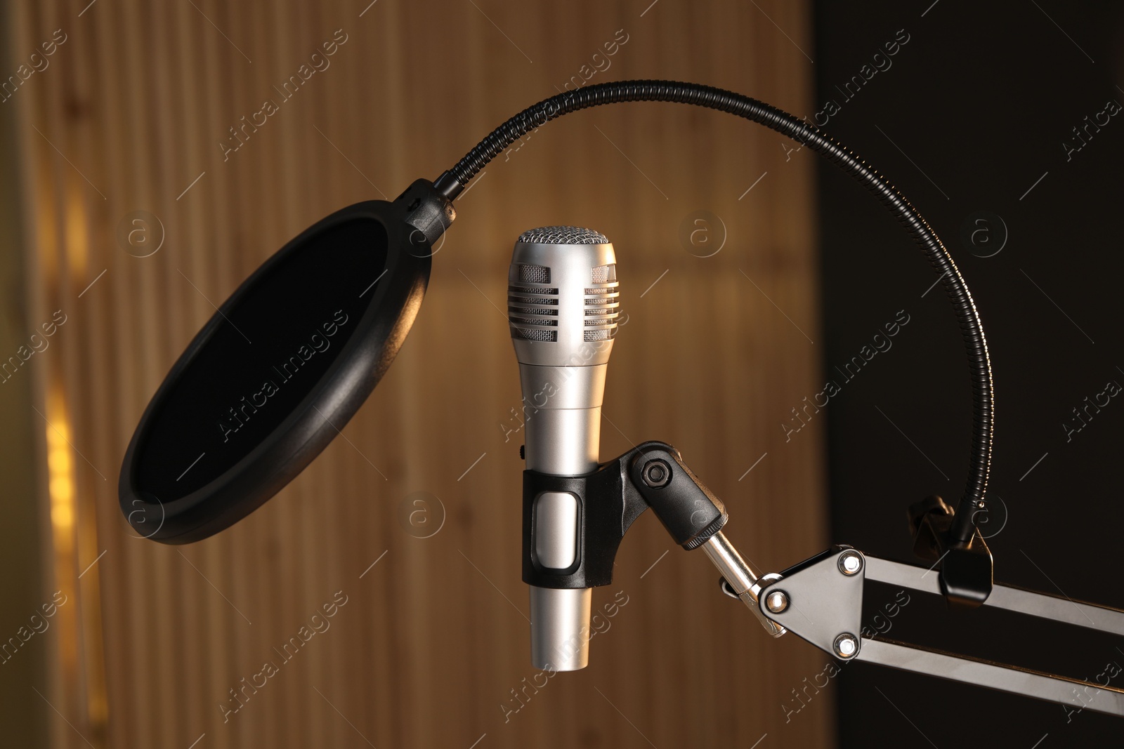 Photo of Stand with microphone and pop filter on blurred background. Sound recording and reinforcement