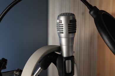 Photo of Stand with microphone and pop filter on blurred background, closeup. Sound recording and reinforcement