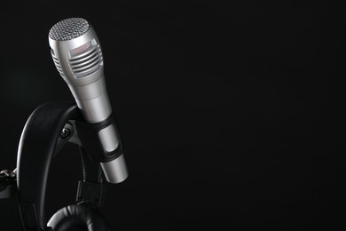 Photo of Stand with microphone and headphones on black background, space for text. Sound recording and reinforcement