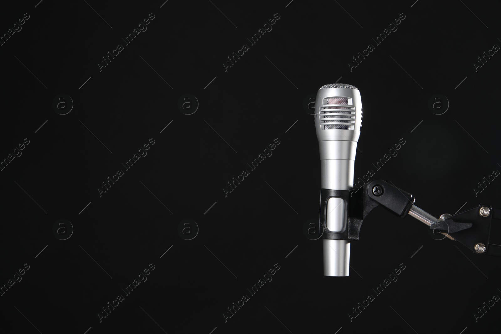 Photo of Stand with microphone on black background, space for text. Sound recording and reinforcement