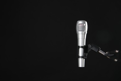 Photo of Stand with microphone on black background, space for text. Sound recording and reinforcement