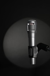 Photo of Stand with microphone in spotlight on black background. Sound recording and reinforcement