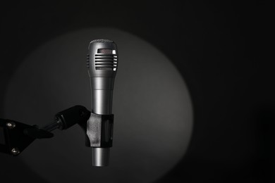 Photo of Stand with microphone in spotlight on black background, space for text. Sound recording and reinforcement