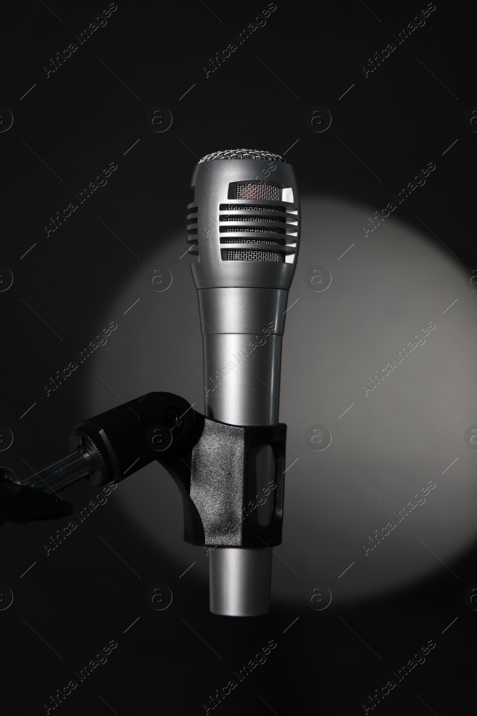 Photo of Stand with microphone in spotlight on black background. Sound recording and reinforcement