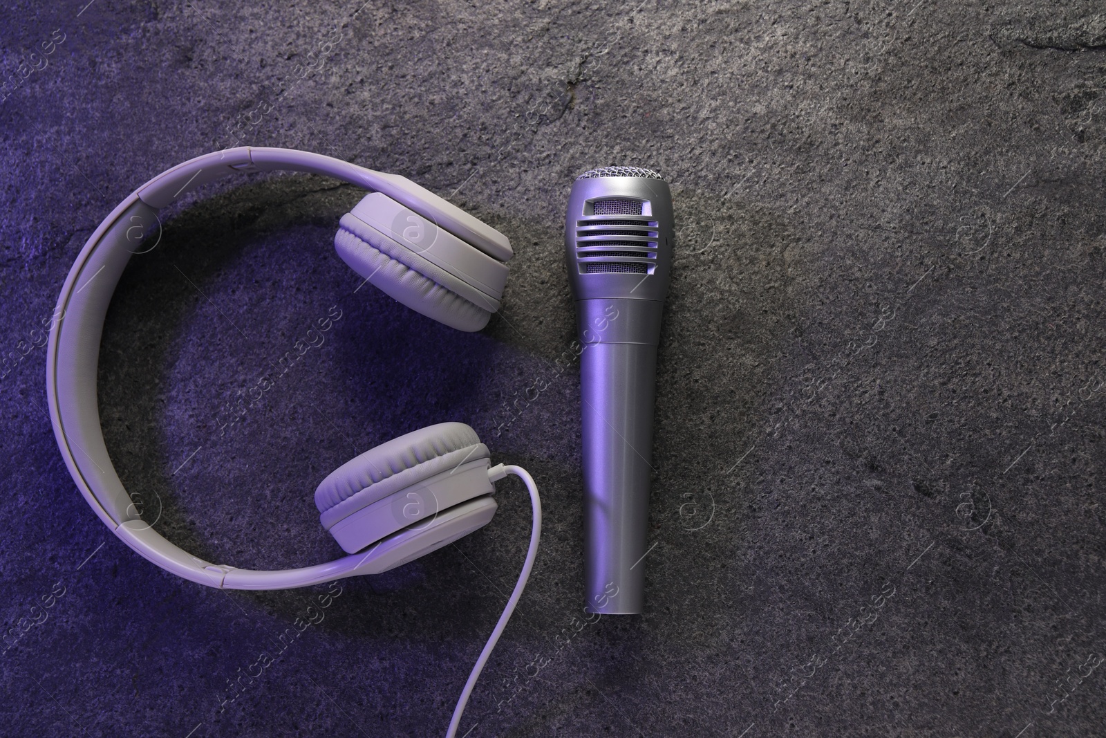 Photo of Microphone and headphones on grey textured background, flat lay with space for text. Sound recording and reinforcement