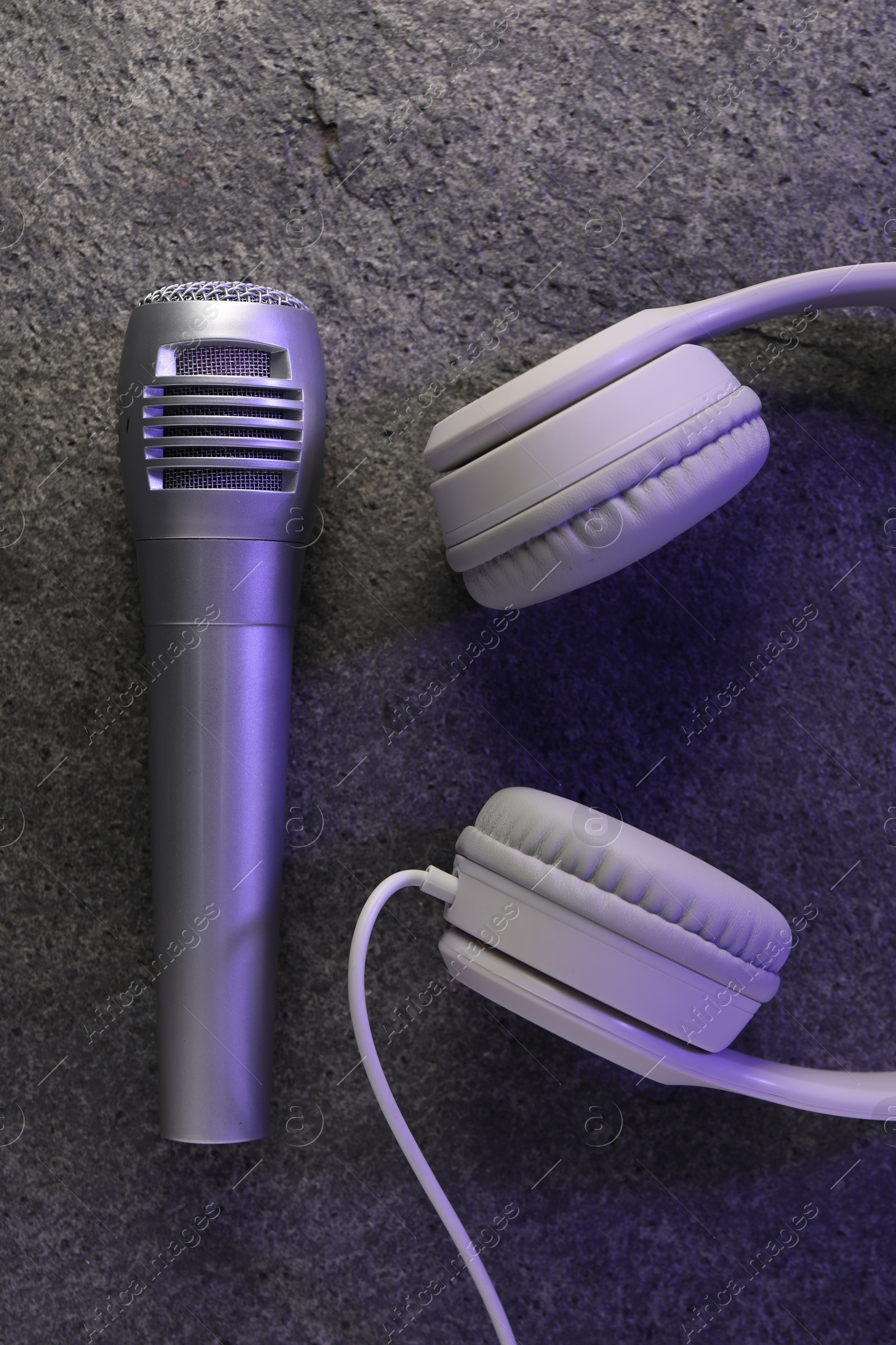 Photo of Microphone and headphones on grey textured background, flat lay. Sound recording and reinforcement