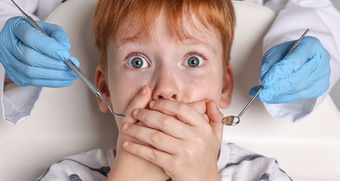 Dental phobia. Dentist working with scared little boy