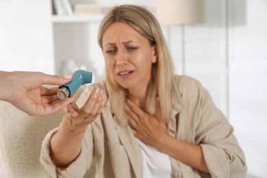 Photo of Woman getting inhaler at home, selective focus. Asthma treatment