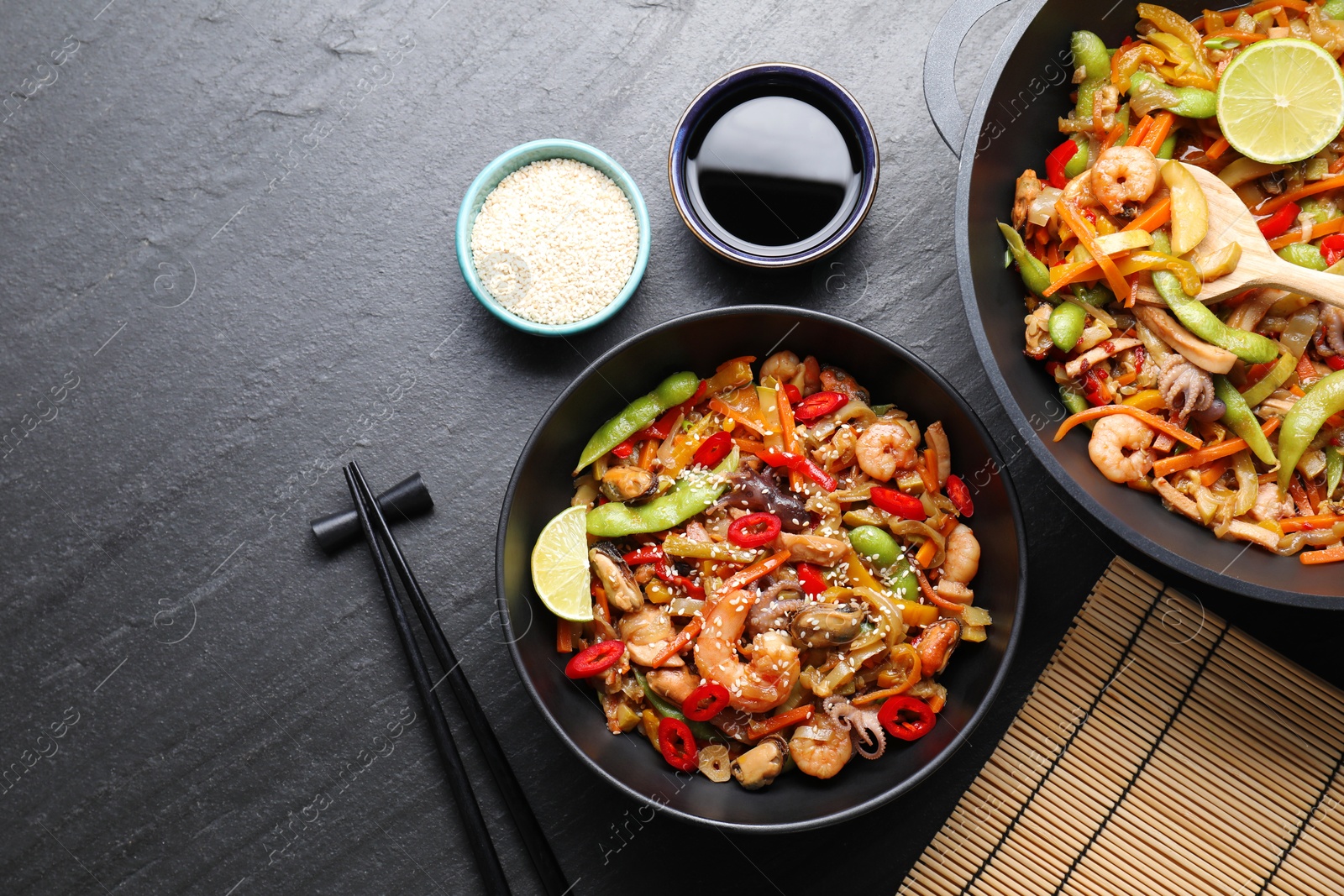 Photo of Stir-fry sea food served on grey textured table, flat lay