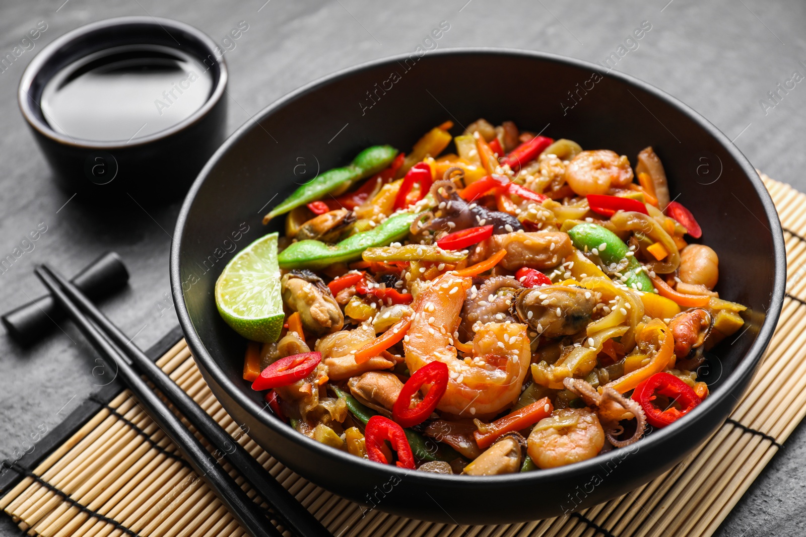 Photo of Stir-fry sea food served on grey table, closeup