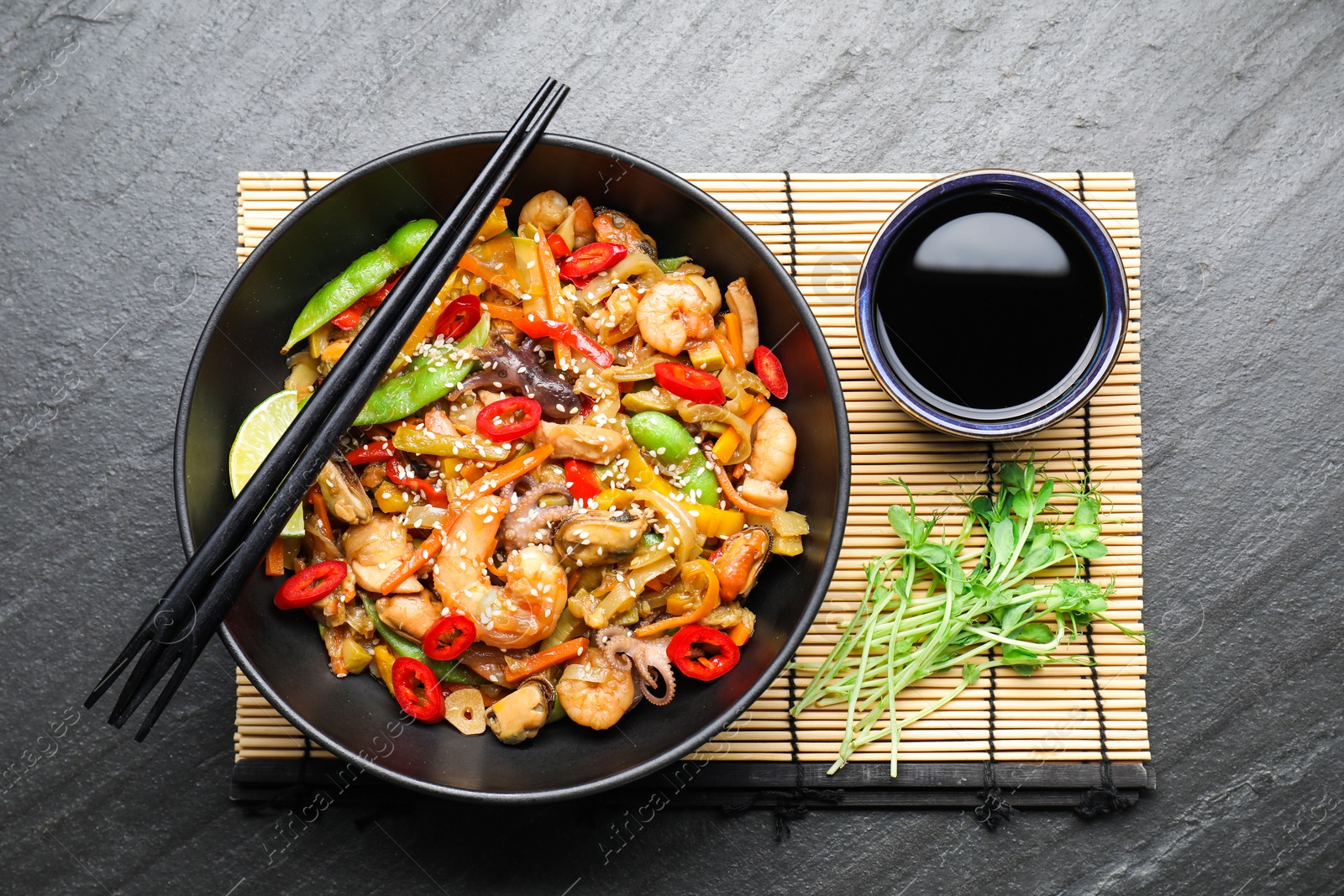 Photo of Stir-fry sea food served on grey textured table, flat lay