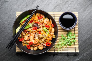 Stir-fry sea food served on grey textured table, flat lay