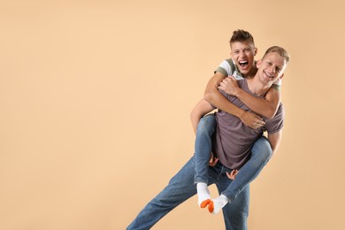 Photo of Happy brothers on beige background. Space for text