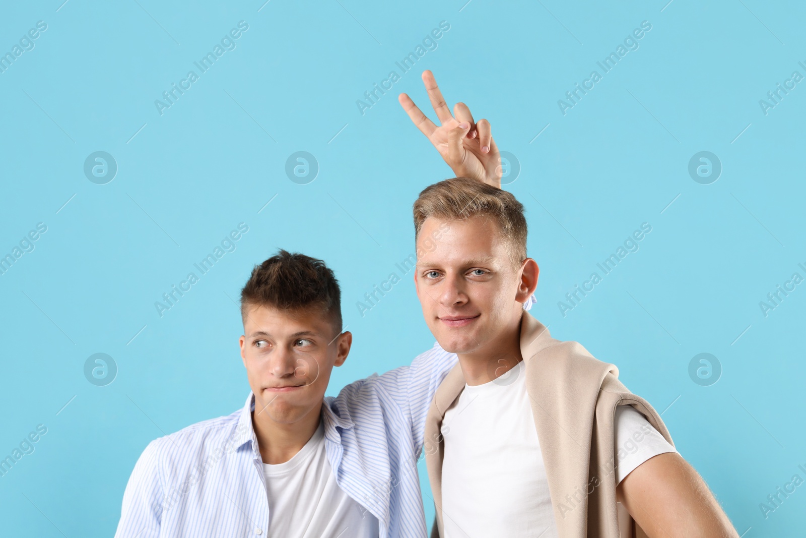 Photo of Portrait of funny brothers on light blue background