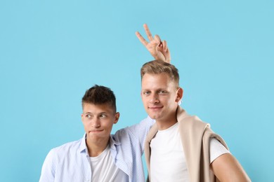 Portrait of funny brothers on light blue background