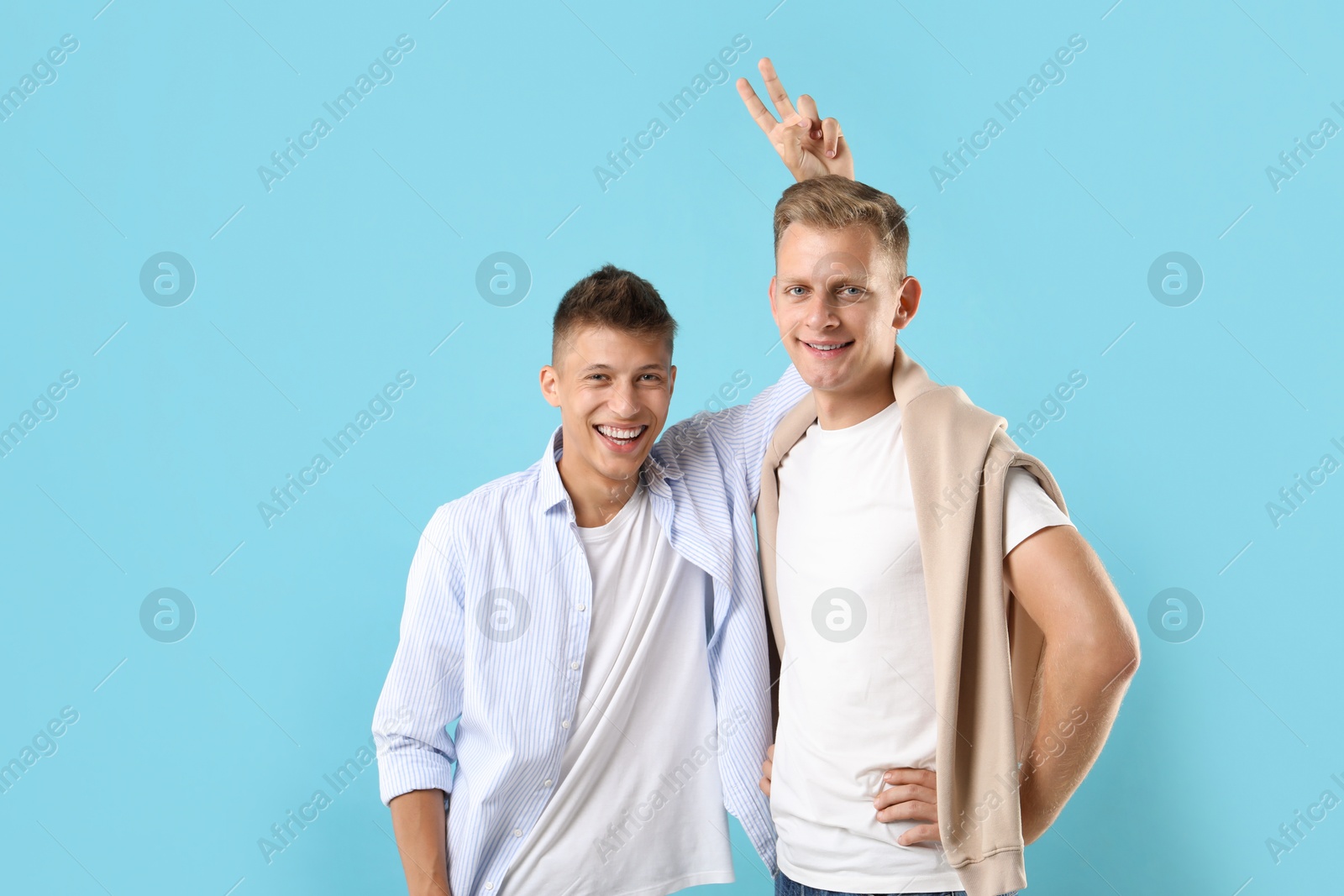 Photo of Portrait of happy brothers on light blue background