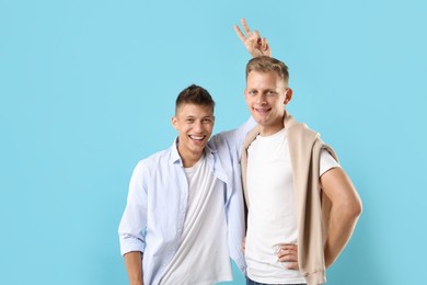 Portrait of happy brothers on light blue background