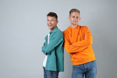 Two happy brothers posing with crossed arms on light background. Space for text