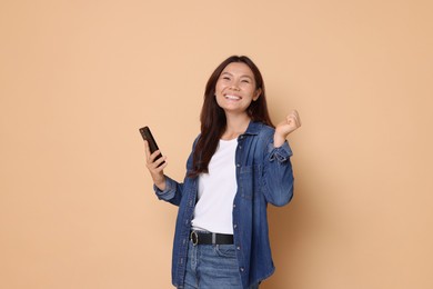 Photo of Smiling woman with smartphone on beige background