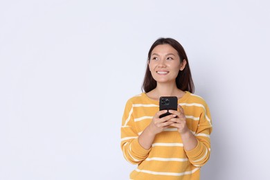 Photo of Smiling woman with smartphone on white background. Space for text