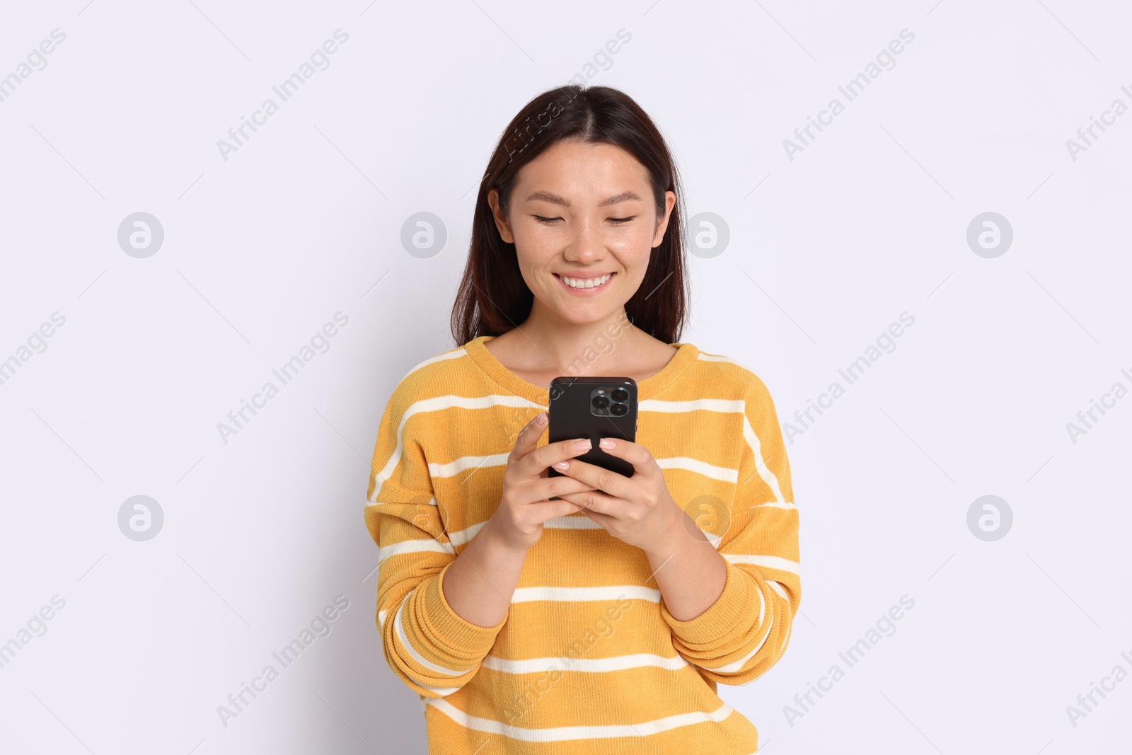 Photo of Smiling woman using smartphone on white background