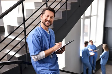 Photo of Healthcare workers in hospital, selective focus. Nurse with clipboard and pen indoors