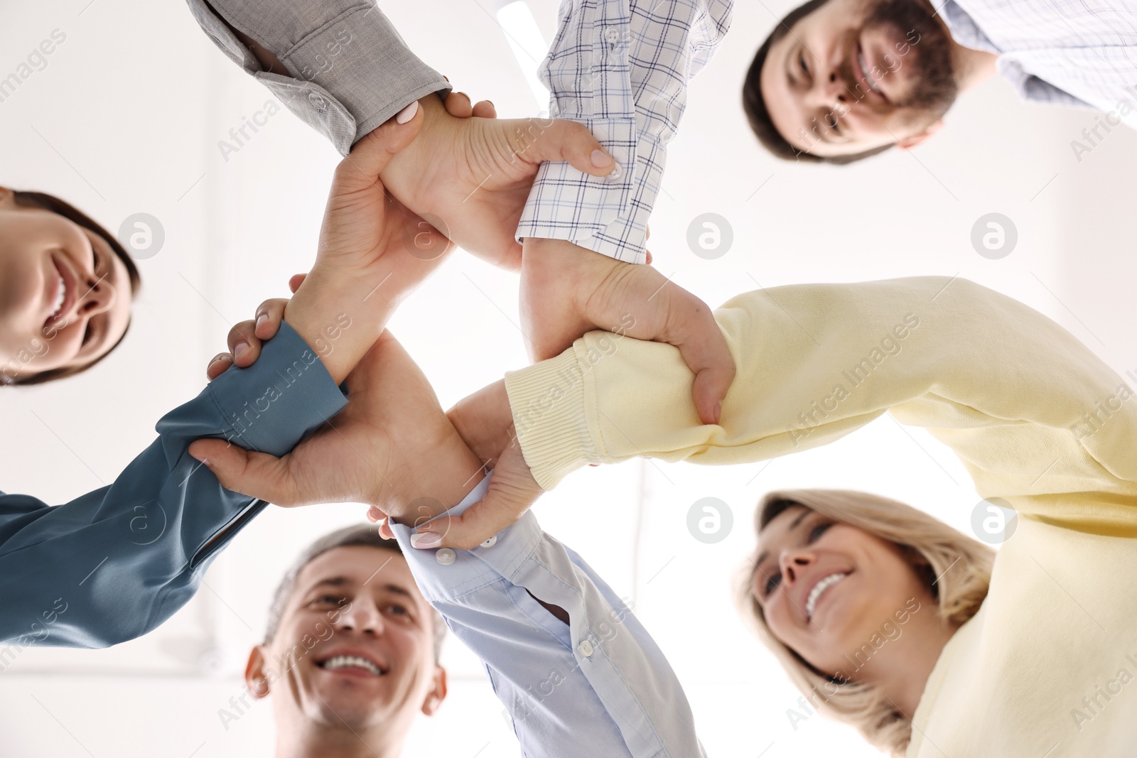 Photo of Teamwork. Group of employees joining hands in office, bottom view