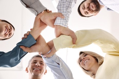 Photo of Teamwork. Group of employees joining hands in office, bottom view