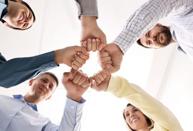 Photo of Teamwork. Group of employees joining hands in office, bottom view